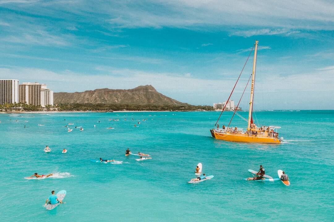 People surfing in Hawaii at Waikiki with Diamond Head in the background
