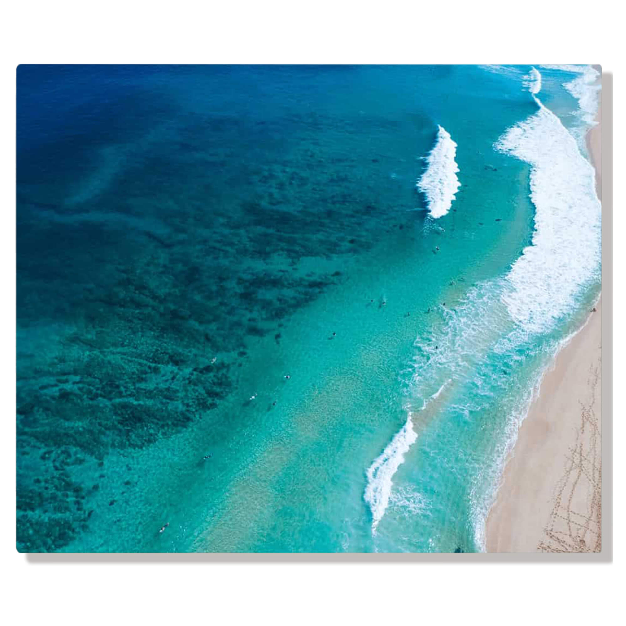 A metal art print of a drone photo of famous waves and surfers near Pupukea by Hawaii artist Bree Poort