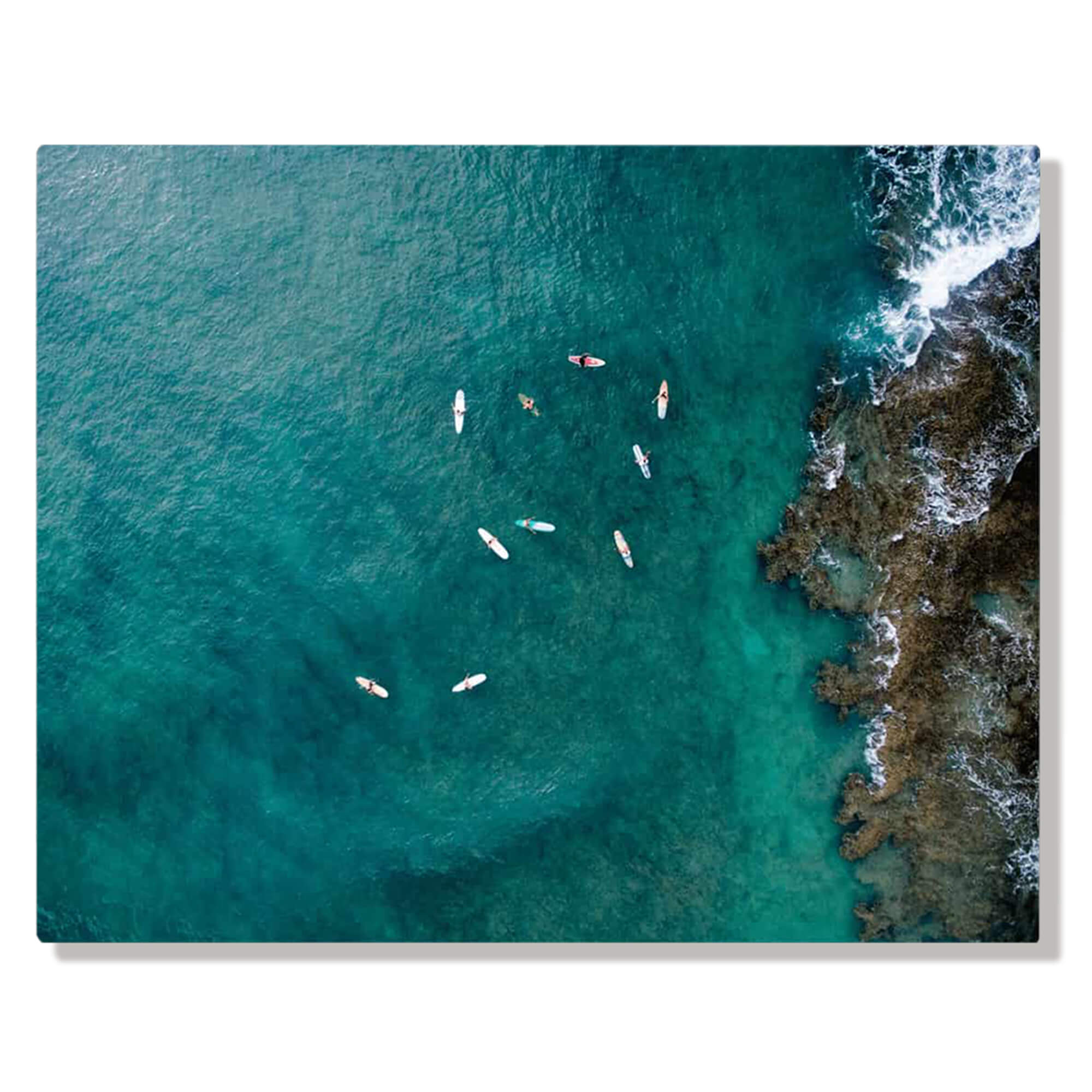 A metal art print of a dramatic aerial seascape print depicts a drone photo of surfers near Turtle Bay on the North Shore of Oahu by Hawaii artist Bree Poort