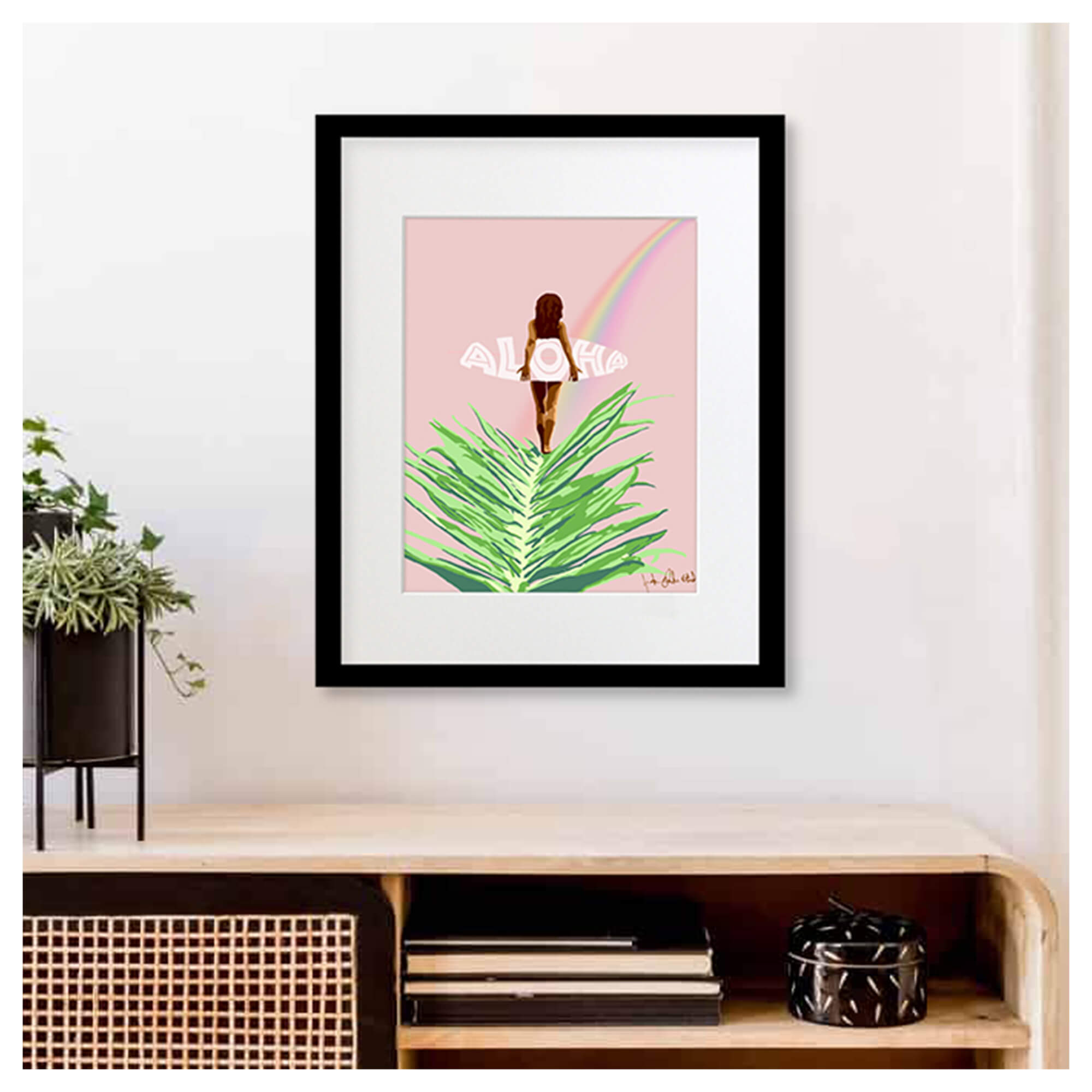 A framed matted art print featuring a woman holding a surfboard following a beautiful rainbow on a pastel pink background by Hawaii artist Jackie Eitel